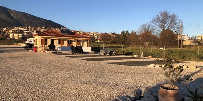 Motorhome parking space - Wintercamping - Greece - Stellplätze mit Sanitäranlagen im Hintergrund  - Camperstop "Kalimera" 