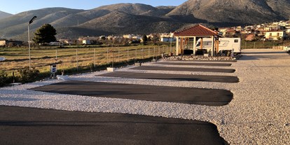 Motorhome parking space - Wintercamping - Greece - Stellplätze mit Aufenthaltraum im Hintergrund  - Camperstop "Kalimera" 