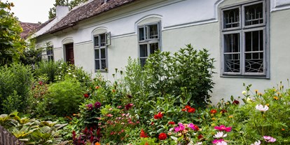 Reisemobilstellplatz - WLAN: nur um die Rezeption vorhanden - Österreich - Sattlerhaus mit blühendem Vorgarten - Museumsdorf Niedersulz