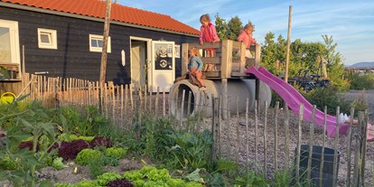Motorhome parking space - Umgebungsschwerpunkt: See - Antwerpen - das Sanitärgebäude mit Gemüsegarten und kleinem Spielplatz - Camping Zeeuws Genieten