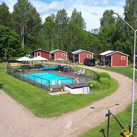 Wohnmobilstellplatz: Lager der Hütten und des Pools. Stellflächen befinden sich am linken Bildrand und rechts des Bildes. - Camping 45