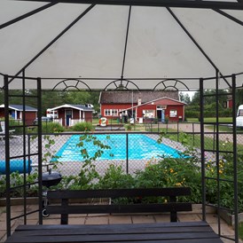 Wohnmobilstellplatz: Grillpavillon und der Pool.  Im Hintergrund das Servicegebäude. - Camping 45