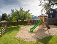 Wohnmobilstellplatz: Abgegrenzter Kinderspielplatz mit Spielturm, Rutsche, Schaukeln, Sitzgelegenheiten, Slackline & Bäumen - Tauerncamping Radstadt