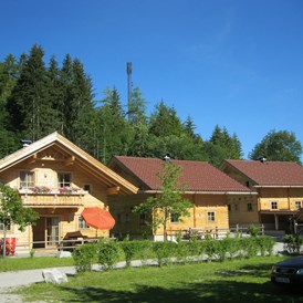 Wohnmobilstellplatz: Holzblockhäuser im Areal des Campingplatzes - Karwendel Camping