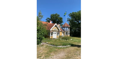 Reisemobilstellplatz - SUP Möglichkeit - Senoren - Wohnhaus mit gehisster schwedischer Flagge - Einzel-Wohnmobilstellplatz auf Halbinsel Knösö