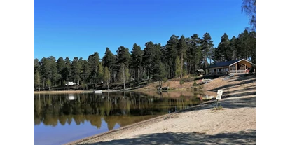 RV park - Wintercamping - Delsbo - Blick vom Sandstrand Richtung Rezeption mit Restaurant und Kiosk, schöne Außenterrasse mit herrlicher Sicht auf See und Umgebung. Blick - Norra Dellen Familjecamping