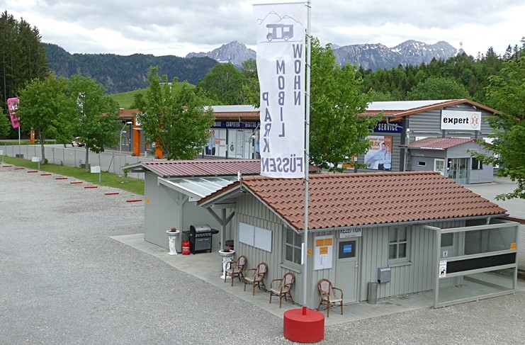 Wohnmobilstellplatz - Auf diesem Bild sehen Sie unser Rezeptionsgebäude mit den Sanitäranlagen dahinter. - Wohnmobilpark Füssen