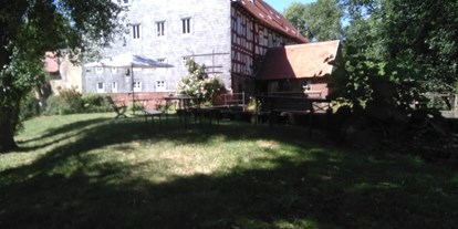 Reisemobilstellplatz - Grünberg (Gießen) - Blick auf die Mühle und das Staubecken. Der obere Teil der Wiese ist sehr schattig den ganzen Tag über (nicht befahrbar, nur Liegewiese od. Campingwiese) - Brücker Mühle