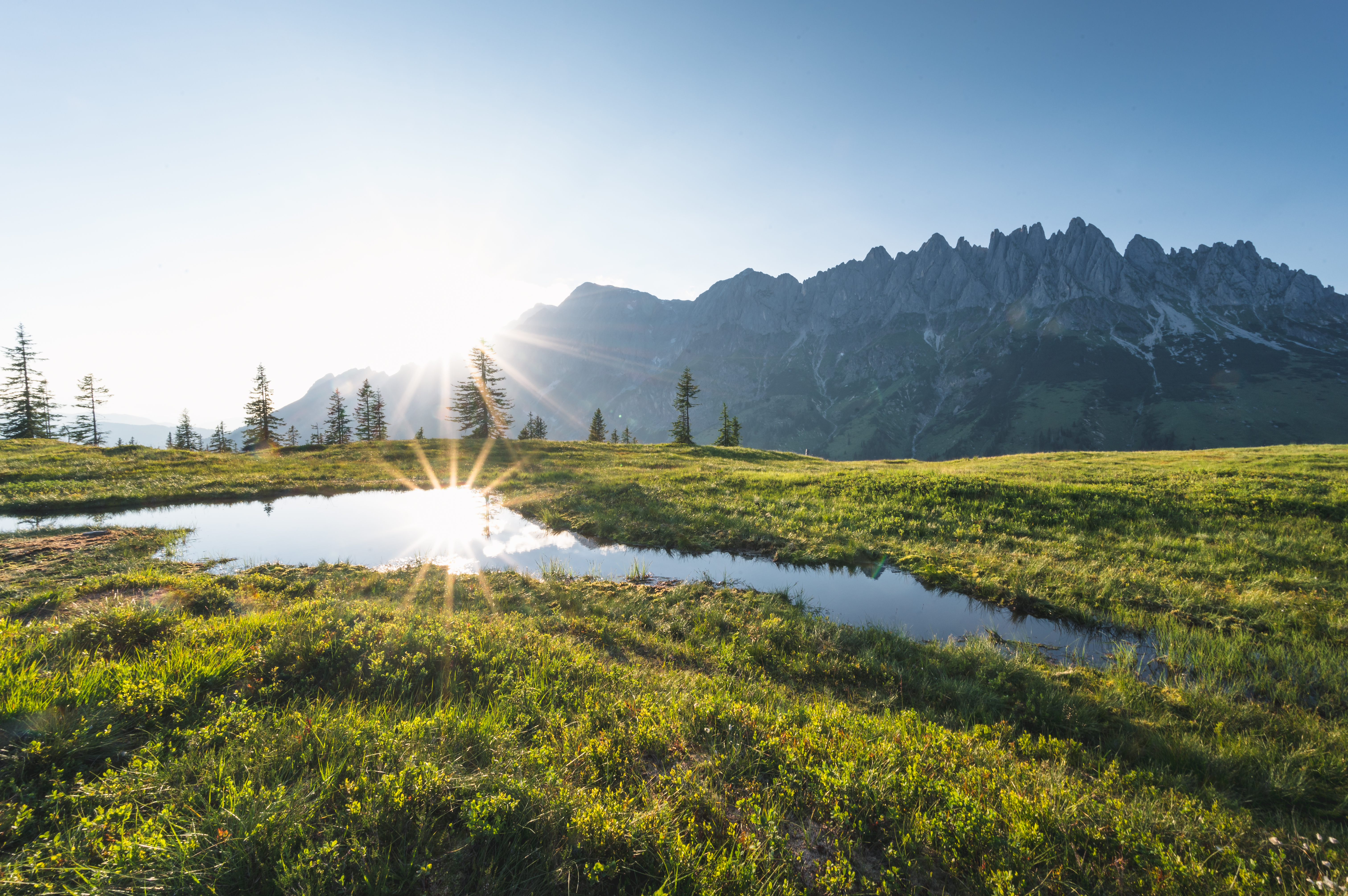 aire de camping-car - TRÄUME WERDEN WAHR 
Sonnenschein auf dem Hochkeilsee umgeben von der grünen Landschaft mit dem Ausblick auf das Bergenparadies - Hochkönig Camping