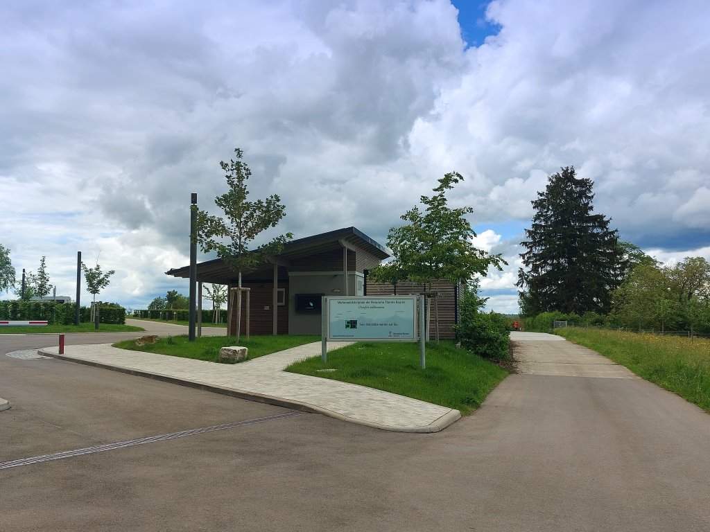 Reisemobilstellplatz: Einfahrtsbereich mit Sanitärgebäude und Müllhäusle - Wohnmobilstellplatz der Panorama Therme Beuren - Infrastructuur, Sanitair, Staanplaatsen