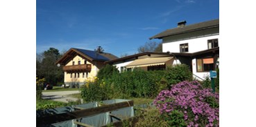 Reisemobilstellplatz - Gschwand - Blick auf Hauptgebäude und modernen und sauberen Waschanlagen, die im gelben Haus mit Sonnenkollektoren zu sehen sind. - Camping Martina