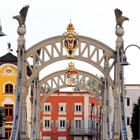 Wohnmobilstellplatz: Länderbrücke mit Kaiserkrone und Wappen von Österreich, sowie Königskrone von Bayern mit dem Bayrischen Wappen - Fischer-Huber-Parkplatz