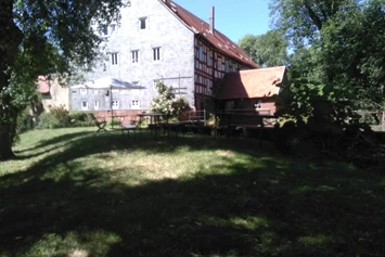 Wohnmobilstellplatz: Blick auf die Mühle und das Staubecken. Der obere Teil der Wiese ist sehr schattig den ganzen Tag über (nicht befahrbar, nur Liegewiese od. Campingwiese) - Brücker Mühle