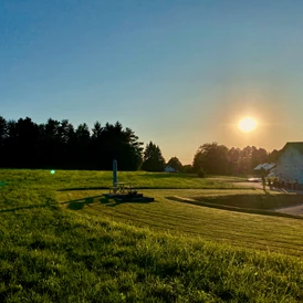 Wohnmobilstellplatz: Blick von der Feuerplatzwiese auf das Anwesen und auf den Schotterstellplatz - Juli 2023 - Camper Stellplatz "VORMFELD"