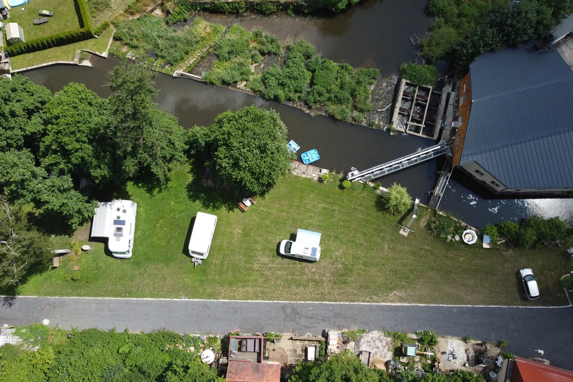 Wohnmobilstellplatz: Luftbild mit den Wohnmobil Stellplätzen (links und Mitte), Parkplätzen für die Autos (rechts) und der Wesenitz - Wohnmobilstellplatz Hofemühle 6x12m Nr. 06