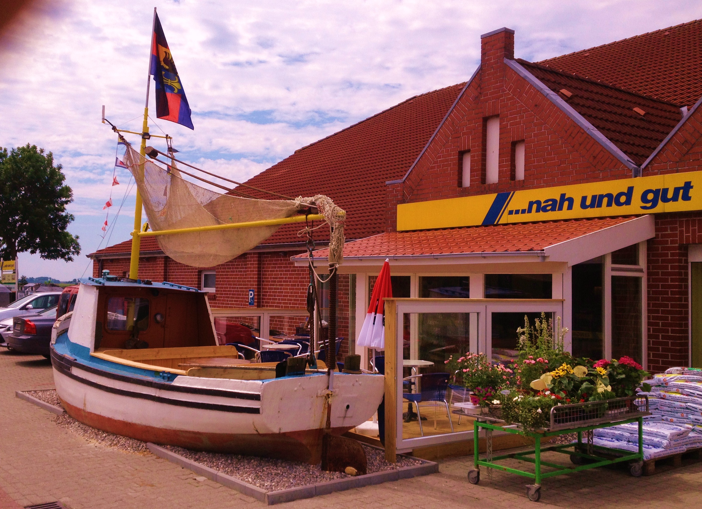 Wohnmobilstellplatz: Ein kleiner Fischkutter dient hier noch als Abgrenzung zu unserem Kutterkaffee. Sie können sich im Kutter und auf der Terasse, soweit es die Witterung zuläßt, mit den leckeren Dingen der Bäckerei verwöhnen. - Ankerplatz Edeka Ditzum