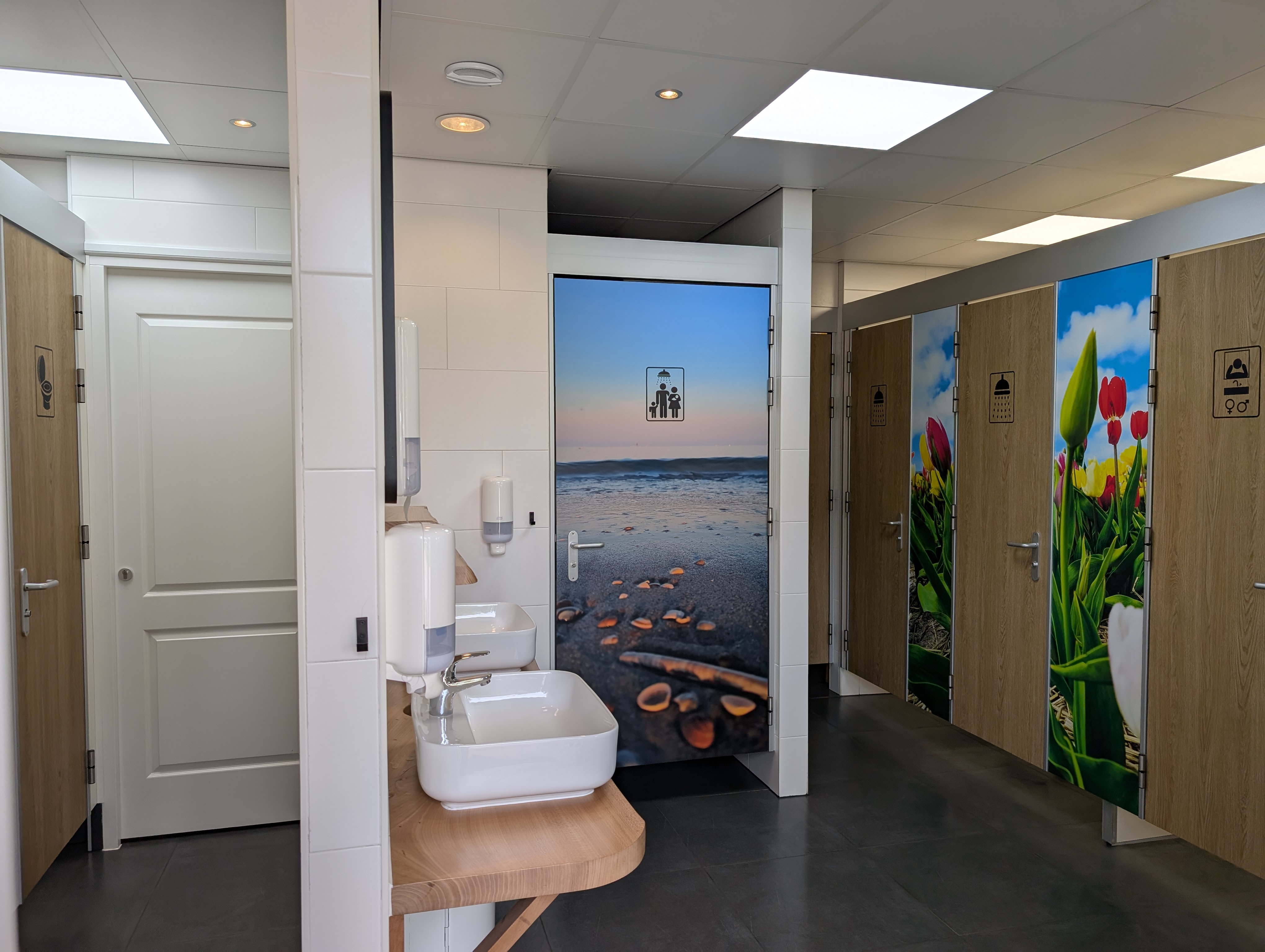 Wohnmobilstellplatz: Beheiztes Sanitärgebäude 3 Toiletten 1 Urinal, 2 Duschen 1 Familiendusche mit 2 Duschen und Wickeltisch, auch für Behinderte geeignet. 2 Waschbecken und 1 Waschbeckenkabine mit Tür. 2 Spülplätze unter dem Vordach 1 Spülplatz im Innenbereich. Waschmaschine und Trockner gegen Gebühr. - Charme Camping ‘t Bullekroffie