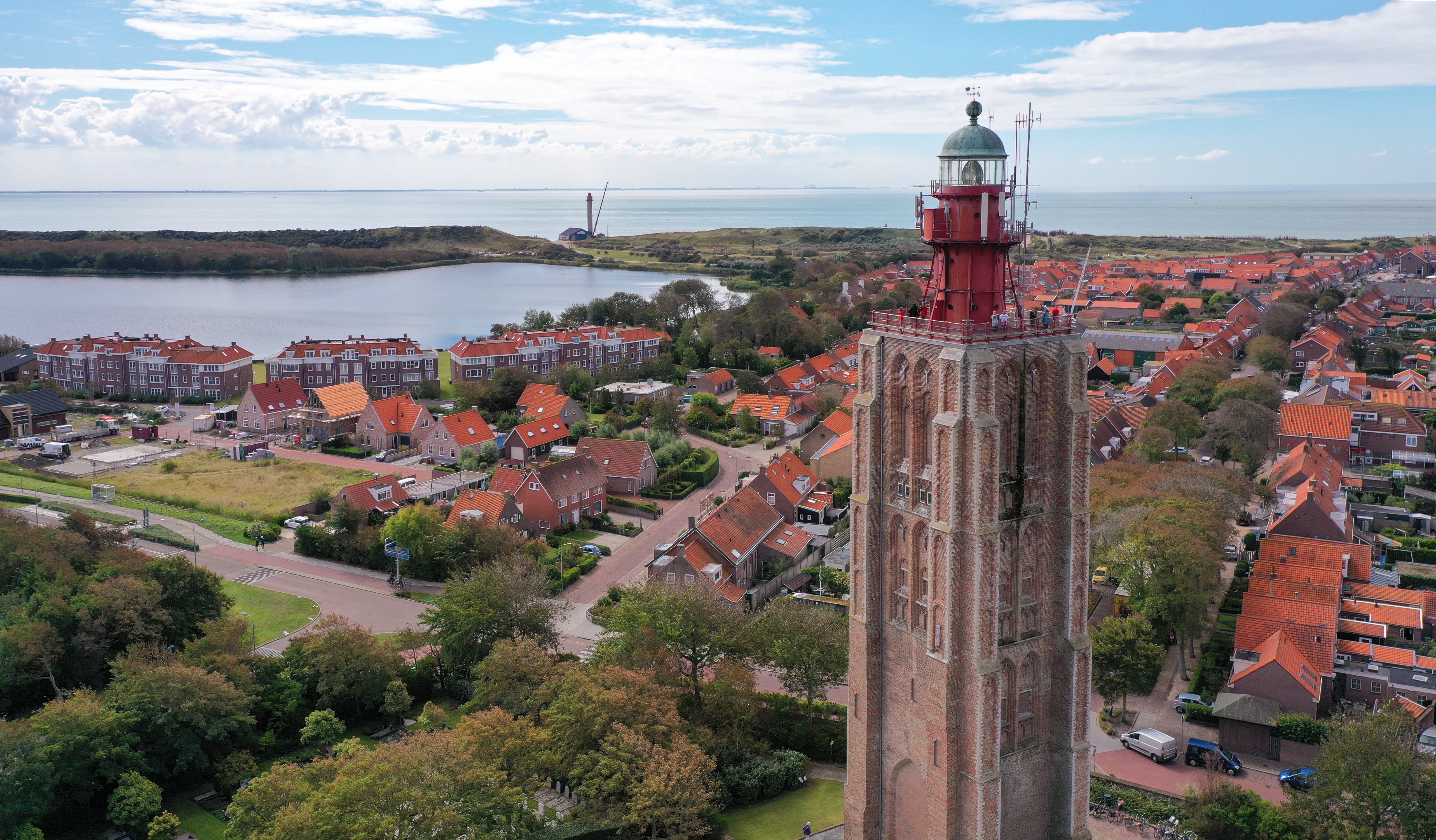Wohnmobilstellplatz: De vuurtoren van Westkapelle, de camping ligt direct aan de voet van de vuurtoren. Op de achtergrond het dorp en de zee  - Minicamping am Leuchtturm