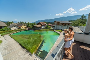 Wohnmobilstellplatz: Ausblick vom AlpinSPA auf den Naturschwimmteich - EuroParcs Hermagor · Nassfeld