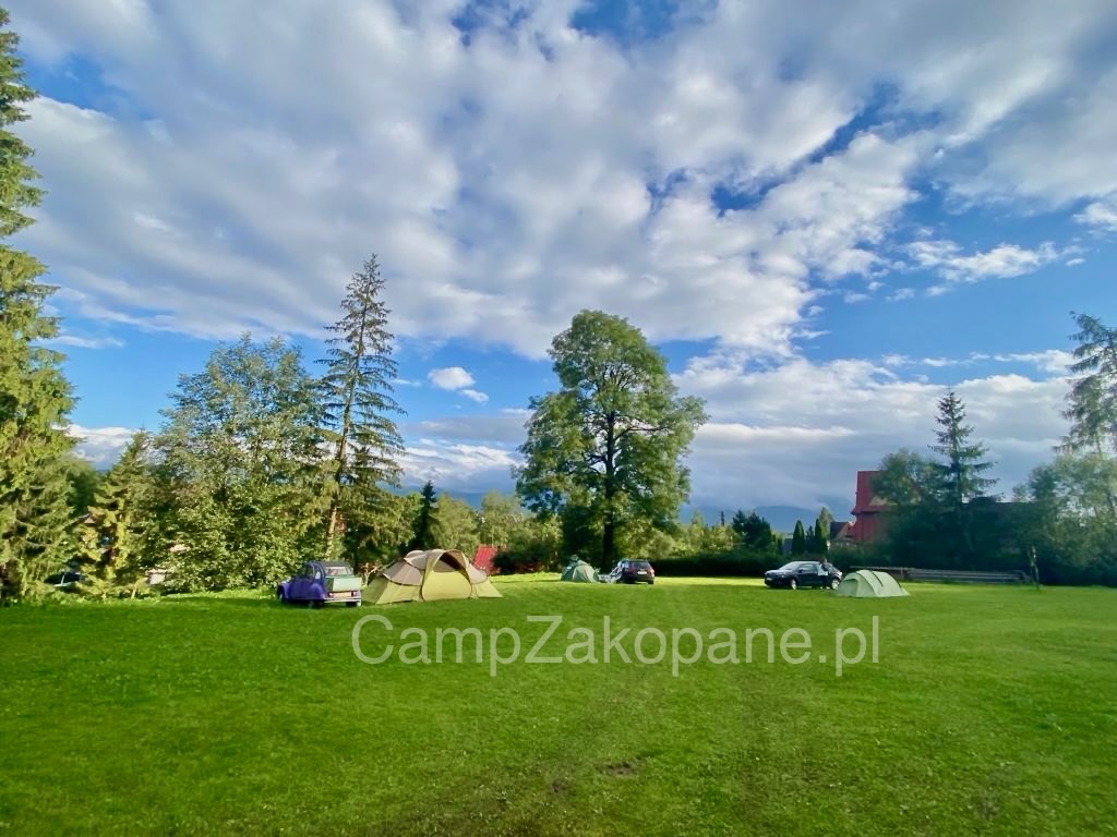 Wohnmobilstellplatz: Sonniger Zeltplatz Camp Harenda Zakopane – Zelte auf grüner Wiese mit Bäumen und bewölktem Himmel - Camp Harenda Zakopane - Vicinanze, zona