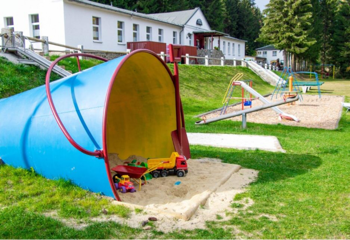 Wohnmobilstellplatz: Blick vom kleinen Spielplatz auf unsere Rezeption im Appartementhaus. Dort befindet sich der Brötchenservice. - Erzgebirgsidyll Breitenbrunn