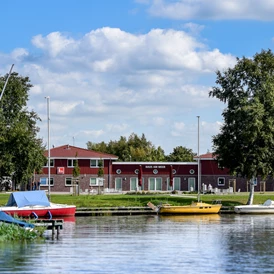 Wohnmobilstellplatz: Das Haus am Meer, hier finden Sie den Sanitärbereich, die Tourist-Information und die Veranstaltungshalle. Der Kiosk mit frischen Brötchen befindet sich direkt daneben. - Wohnmobilhafen Großes Meer