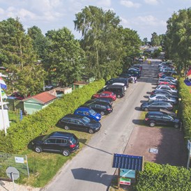 Wohnmobilstellplatz: Kostenloser Parkplatz und Einfahrt zum Campingplatz. vorn links eins unserer Miet Mobilheime. - Campingplatz Blauer See / Reisemobilstellplatz am Blauen See